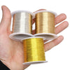 A hand holds three spools of copper clad steel sculpting wire in various shades of gold and silver.