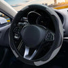 Close-up view of a black steering wheel with a textured leather cover and controls inside a car interior.