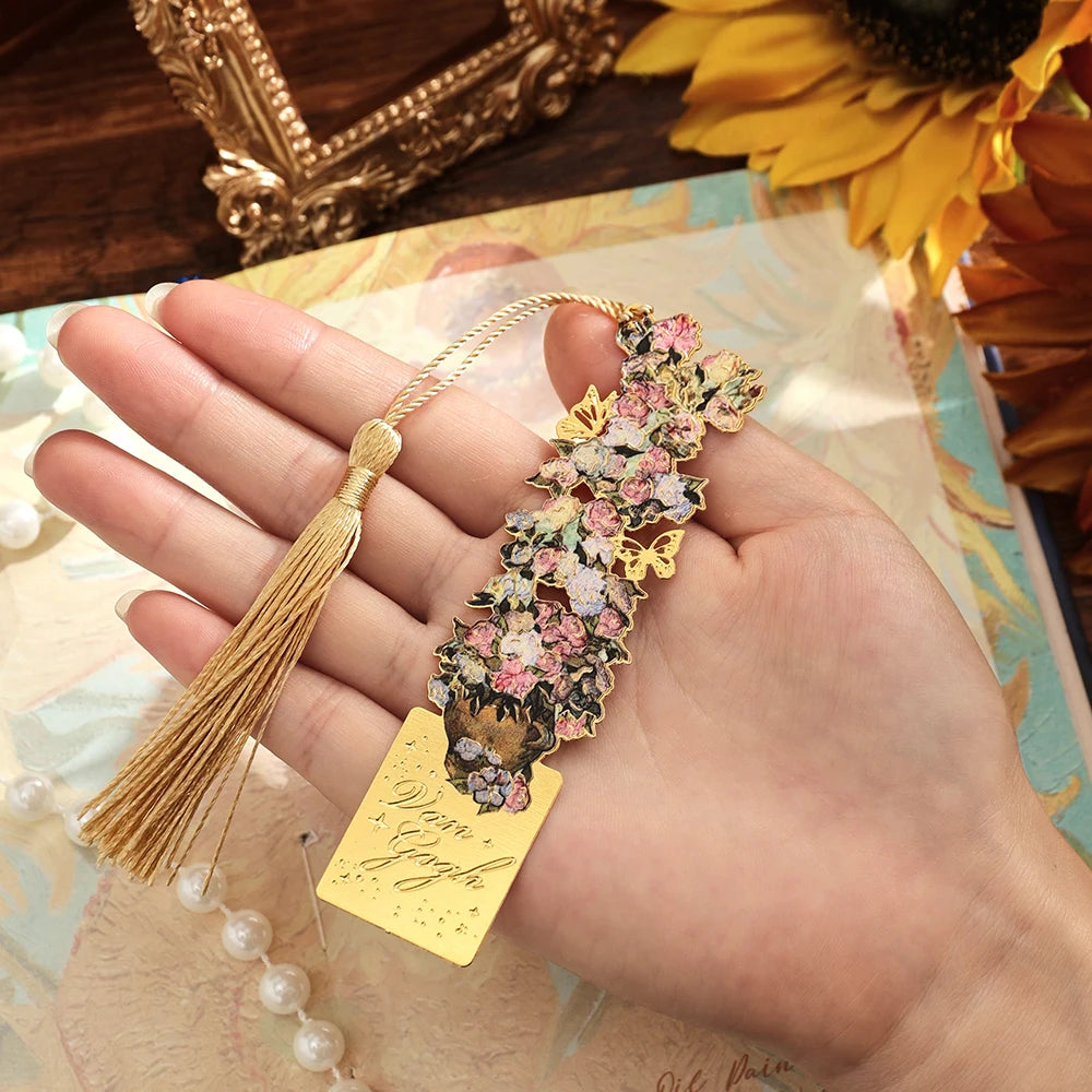 A hand holds a vintage metal bookmark with an artistic hollow design and gold tassel on a light background.