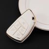A white durable TPU car key fob cover with a gold rim and various buttons is shown resting on a dark surface.