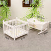 White wooden baby cradle with decorative railing and greenery in a nursery setting