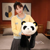 A young woman holding a black and white giant soft panda plush toy.