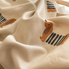 A close-up of a beige fabric with an orange dog print featuring stripes, showing soft folds and texture.