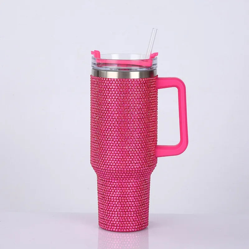 A pink rhinestone bling tumbler with a straw and handle is shown against a white background.