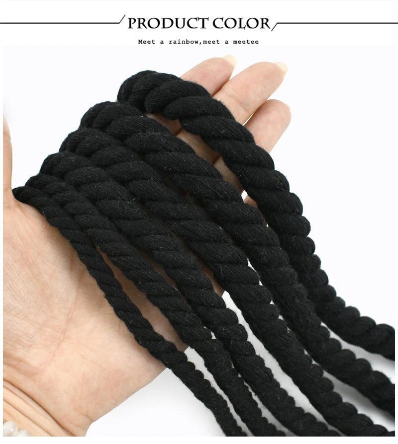 A hand is holding several strands of black natural twisted cotton cord.