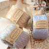 A stack of light blue yarn balls for knitting and crochet displayed on a textured fabric.