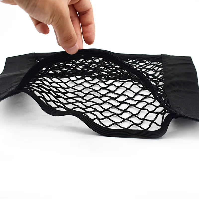 A hand is holding an elastic mesh storage organizer for a car seat back.