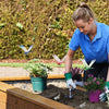 A woman is planting a plant in the garden using lifelike dragonfly clips for decoration.
