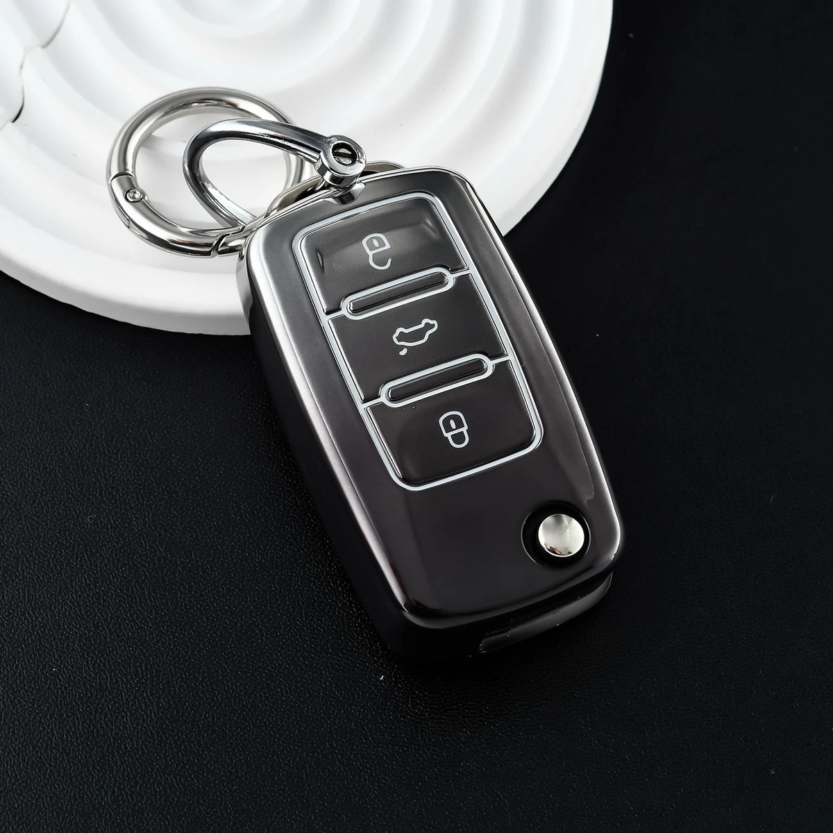 A silver key fob with a metal split ring attached, resting on a white surface.