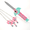 A set of four pink and teal dagger key necklaces with silver charms and a large gray knife.
