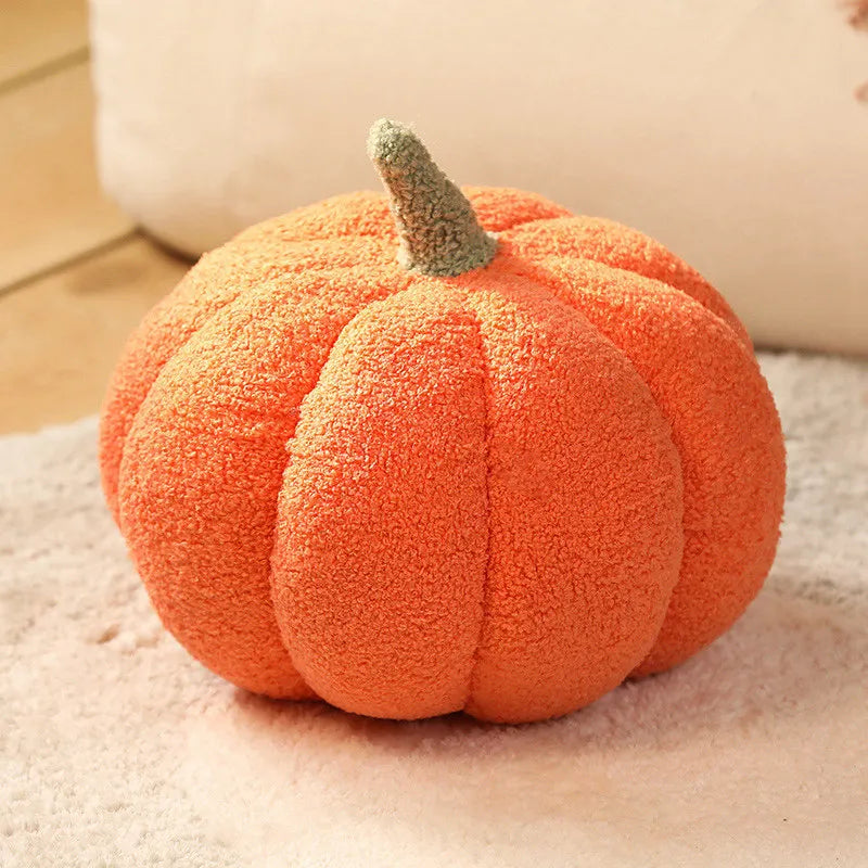 An orange fuzzy pumpkin plush cushion with a green stem resting on a light surface.