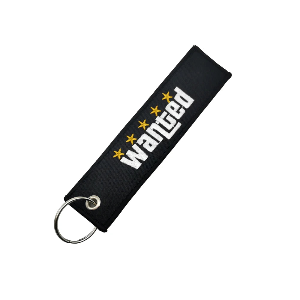 Black nylon keychain with embroidered wanted text and a steel spring clip