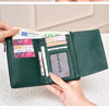 A close-up of a dark green tri-fold wallet with a zipper pocket and a brown leather wallet.