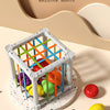A white cube shaped like a house is filled with colorful fruit shapes, demonstrating a rainbow color sorting toy.