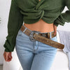 A close-up of a woman wearing a denim shirt and jeans with a brown leather belt and antique silver buckle.