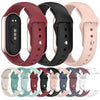 Various silicone replacement straps for Mi Band watches in shades of red, black, and pink.