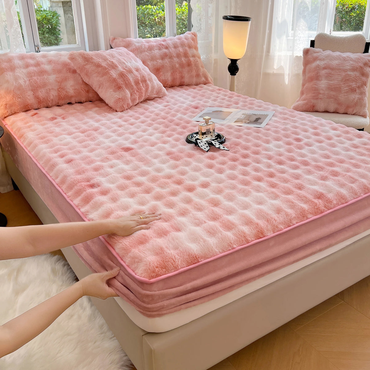 A pink luxury faux fur fitted sheet and pillowcase set displayed on a bed with natural light.