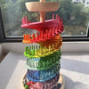 Buntes Holz-Marblaufwerk in Regenbogenform mit gestapelten Blüten und einem Holzbaum als Dach.