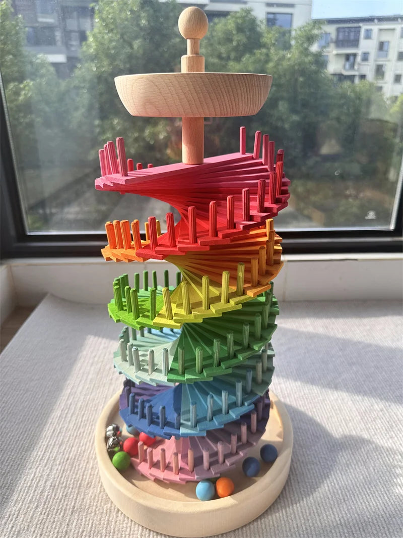 Buntes Holz-Marblaufwerk in Regenbogenform mit gestapelten Blüten und einem Holzbaum als Dach.