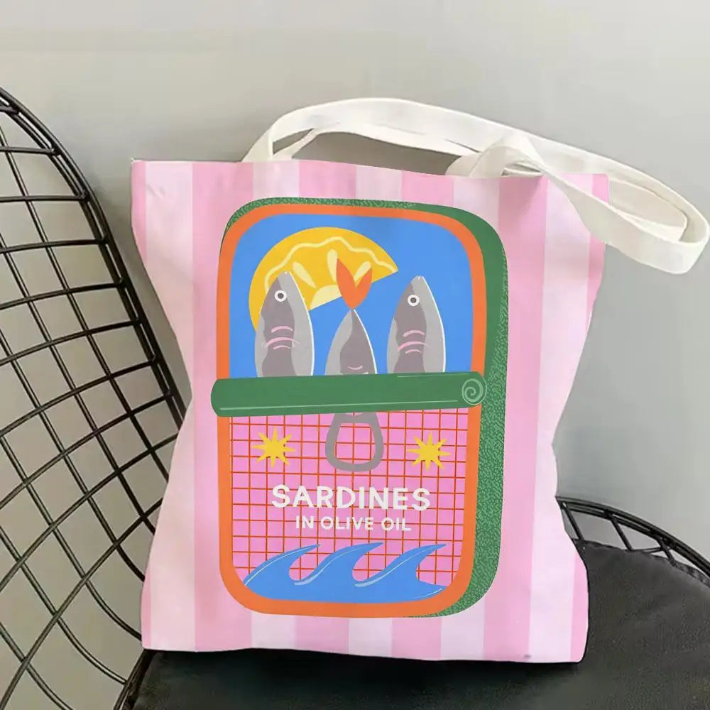 A pink and striped canvas tote bag featuring a graphic print of sardines in olive oil.