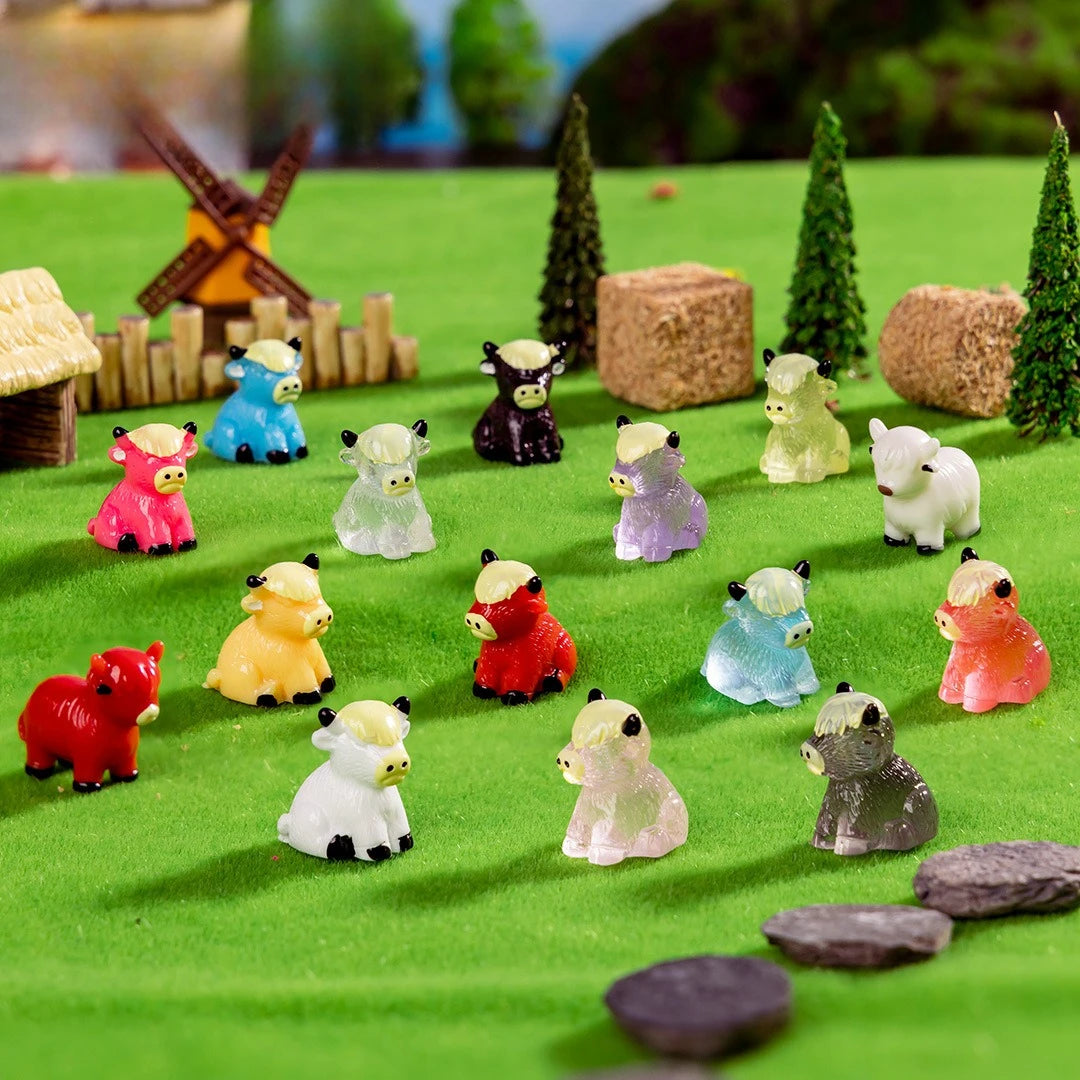 A collection of adorable resin Highland cow figurines in various colors and sizes displayed on green mossy terrain.