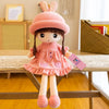 A pink rabbit fairy plush doll with large ears and a dress sitting on a wooden table.