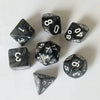 A set of seven black and white polyhedral dice, including a d10, d8, d6, d4, and d20.