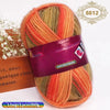 A ball of gradient dyed wool blend yarn in shades of orange, green, and yellow is shown next to a wooden box.