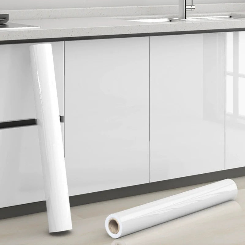 Roll of white pearl finish waterproof self-adhesive wallpaper next to a kitchen countertop.