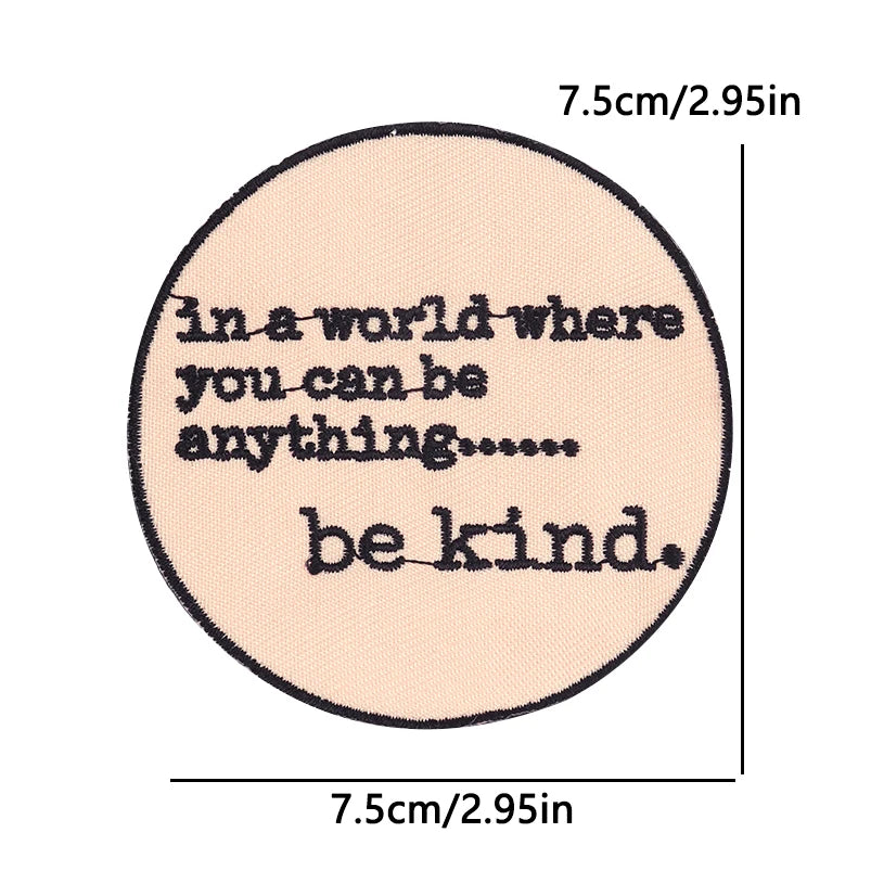 A circular patch with embroidered text that reads in a world where you can be anything be kind