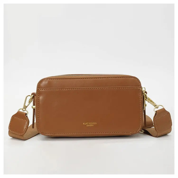 Braune Leder-Tasche mit Signaturbrief-Detail und passender Lederriemen.