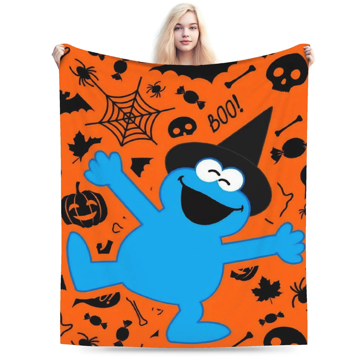 A bright orange flannel throw blanket featuring a cartoon blue monster character and Halloween-themed graphics.