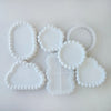 A collection of white silicone tray molds with various scalloped and textured edges for crafting projects.