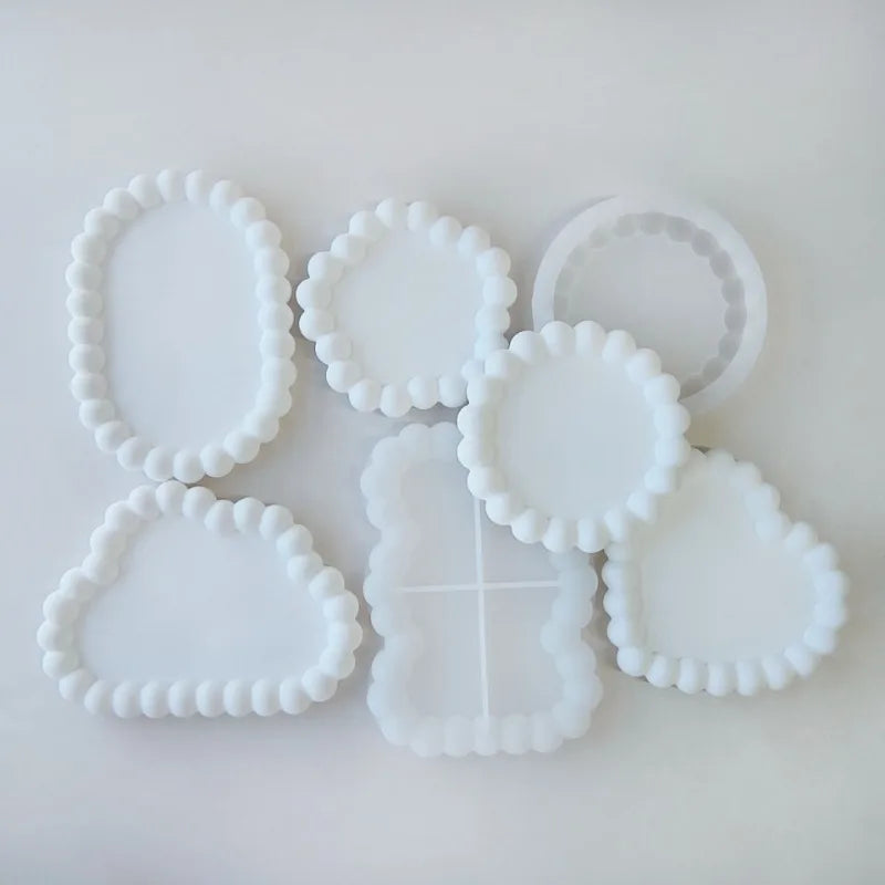 A collection of white silicone tray molds with various scalloped and textured edges for crafting projects.