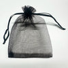 A sheer black organza drawstring bag with a black tassel, displayed against a white background.