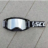A pair of black SCOTT motocross goggles resting on a gray concrete surface.