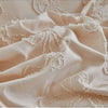 Close-up of a beige linen duvet cover featuring delicate white lace trim and folds.