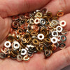 A handful of round acrylic spacer beads in various gold and silver tones held in a person's hand.