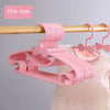 Pink plastic hangers with bow designs hanging from a wooden rod.