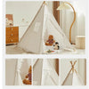A white foldable play tent with sheer curtains is set up indoors next to a wooden dresser and a floor lamp.