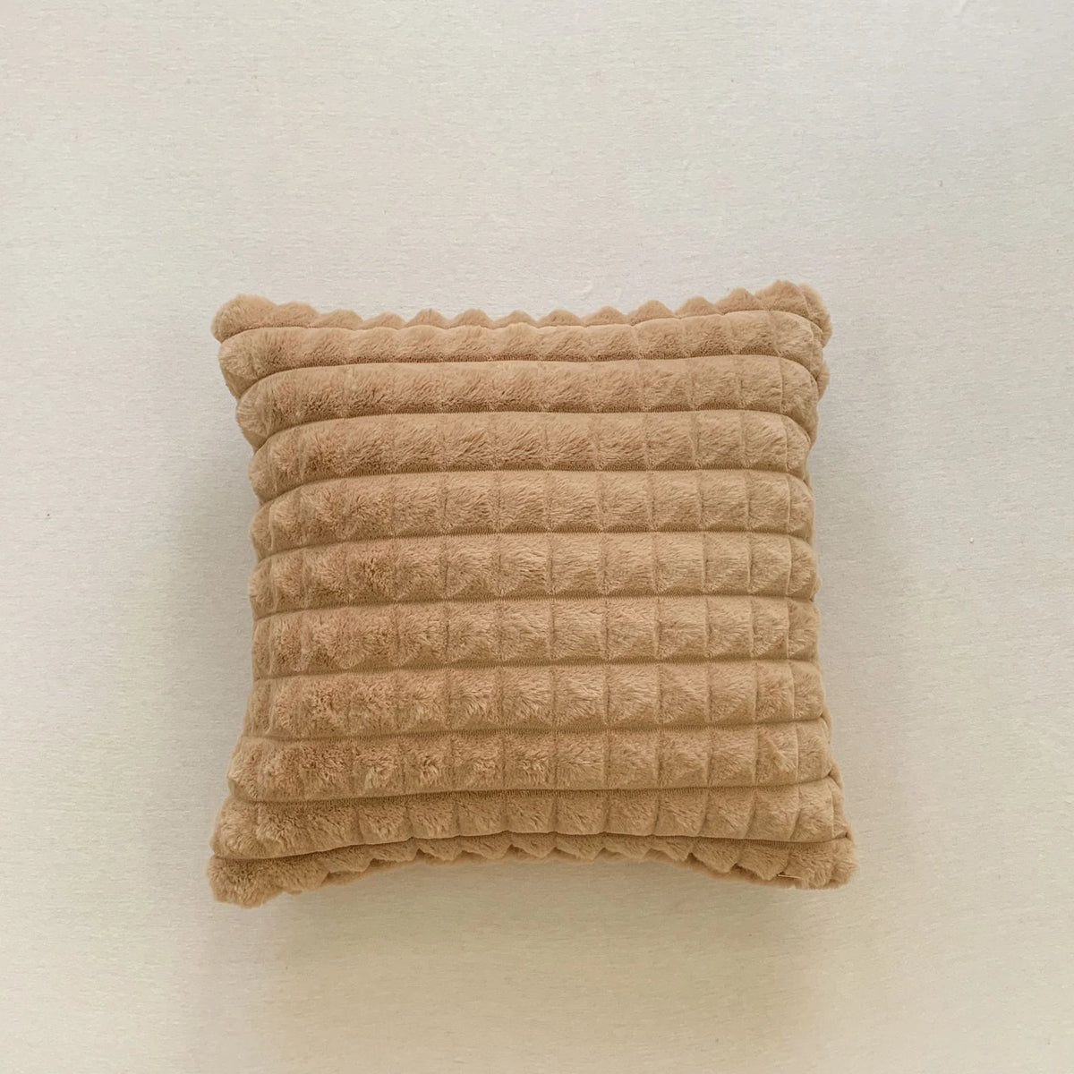 A rectangular, textured beige plush pillow cover with horizontal ribbing.