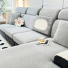 A light gray elegant jacquard sofa slipcover with decorative pillows and a textured fabric on a modern couch.
