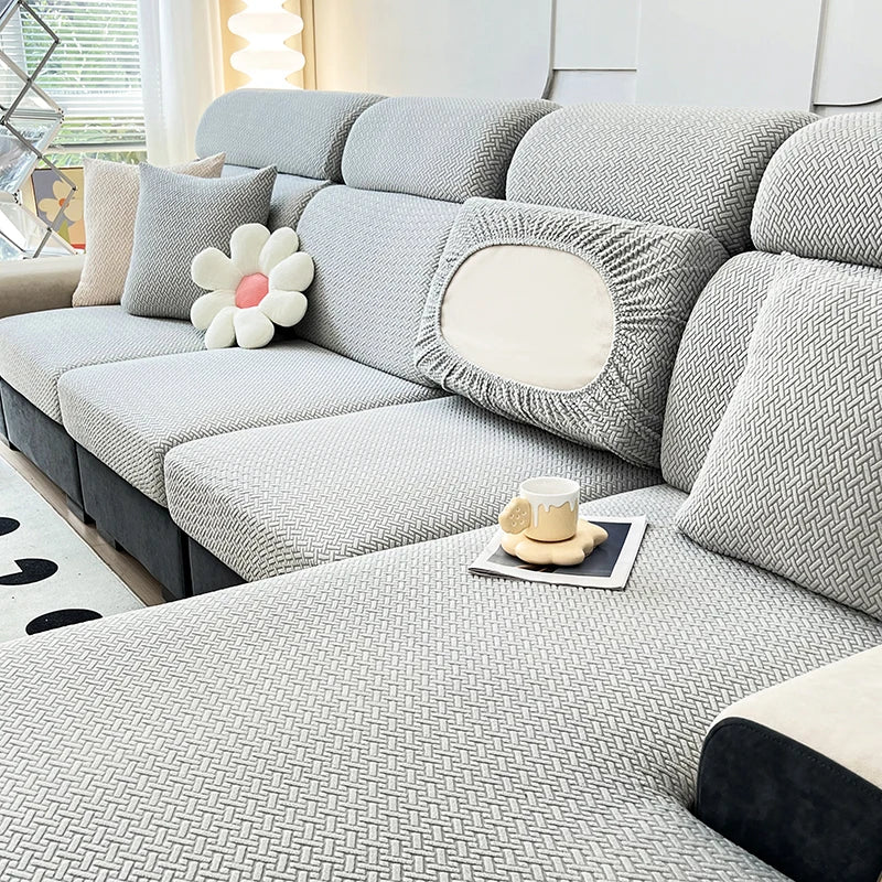 A light gray elegant jacquard sofa slipcover with decorative pillows and a textured fabric on a modern couch.