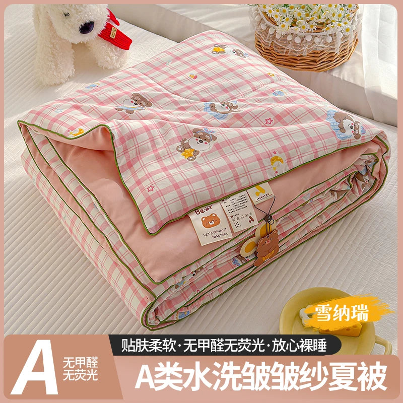 A lightweight summer quilt with a pink and white checkered pattern featuring playful cartoon prints.