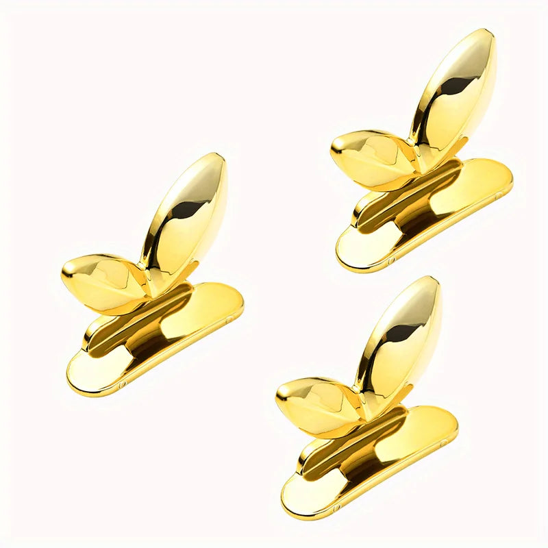 A pair of gold-colored touch-free toilet seat lifters with flush buttons.