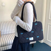 A person is holding a black quilted laptop shoulder bag with blue bows and padded protection.