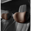 A close-up view of a brown memory foam car headrest and lumbar support pillow installed in a dark gray car seat.