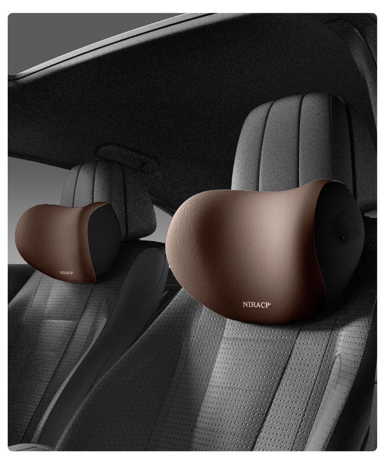 A close-up view of a brown memory foam car headrest and lumbar support pillow installed in a dark gray car seat.