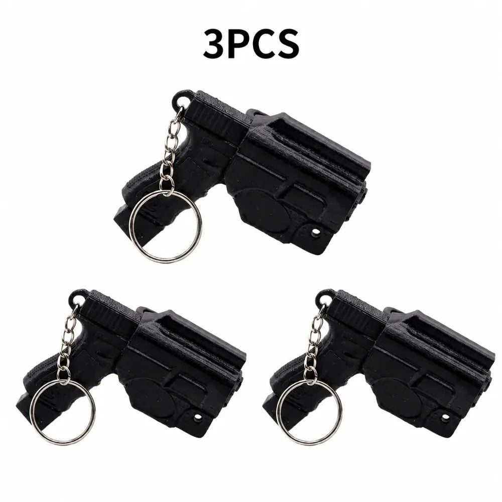 A set of three black mini pistol-shaped keychain accessories with silver chains.