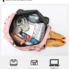 Pink travel duffel bag showing various items like camera, laptop, pants, and coat inside.
